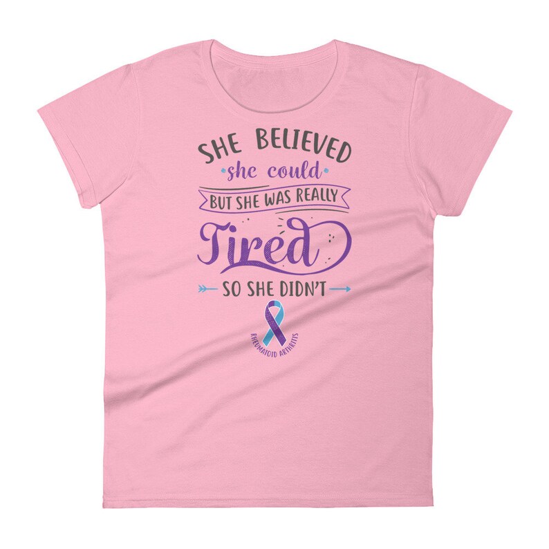 May include: Pink women's t-shirt with a purple and blue ribbon and the text "SHE BELIEVED she could BUT SHE WAS REALLY Tired SO SHE DIDN'T" with arrows pointing to the text. The ribbon says "RHEUMATOID ARTHRITIS".