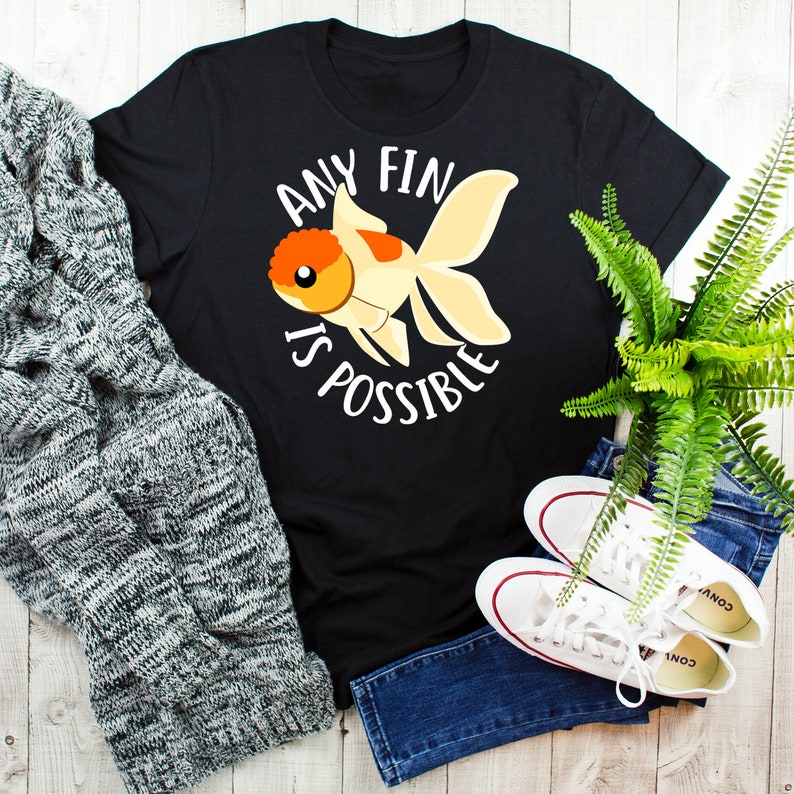 May include: Black t-shirt with a white graphic of a goldfish and the text "Any Fin Is Possible".