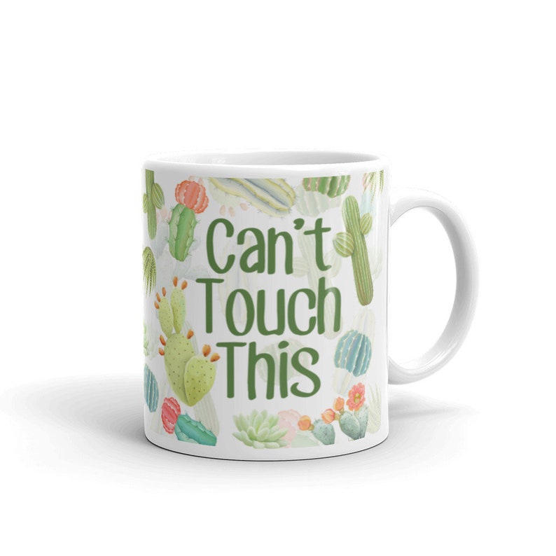 May include: White ceramic mug with a green and white cactus print and the text "Can't Touch This".