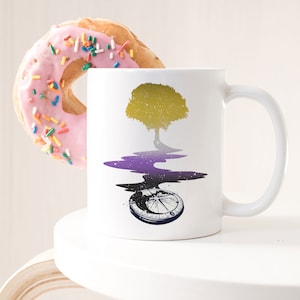 May include: White ceramic mug with a design of a yellow tree with purple and black galaxy-like water flowing from its roots. The water flows into a compass with a black and white design.