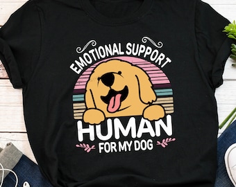 May include: Black t-shirt with a retro-style graphic of a golden retriever dog. The graphic says "Emotional Support Human for My Dog".