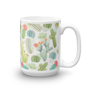 May include: White ceramic mug with a colorful cactus pattern. The mug features a variety of cacti in different shapes and sizes, including prickly pear, barrel cactus, and saguaro. The cacti are painted in shades of green, pink, and yellow.