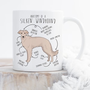 May include: White ceramic mug with a cartoon illustration of a Silken Windhound dog. The illustration is labeled with humorous anatomical features, such as "40% Snoot", "Endless Silky Fluff", "Bonus Fluff", "60% Legs", "Zooming Sticks", "Feather Duster", "Sadness Detector", "Thinking About Velcroing Themselves to You", and "Mood-Ometer".
