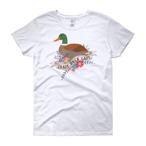 Puede incluir: Camiseta blanca con una ilustraci&oacute;n colorida de un pato con el texto "Crazy Duck Lady" en una pancarta.
