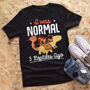 Könnte beinhalten: Schwarzes T-Shirt mit dem Text "Ich war NORMAL vor 3 Reptilien" und einem Cartoon-Bild einer Schlange, einer Schildkröte und eines Axolotls.