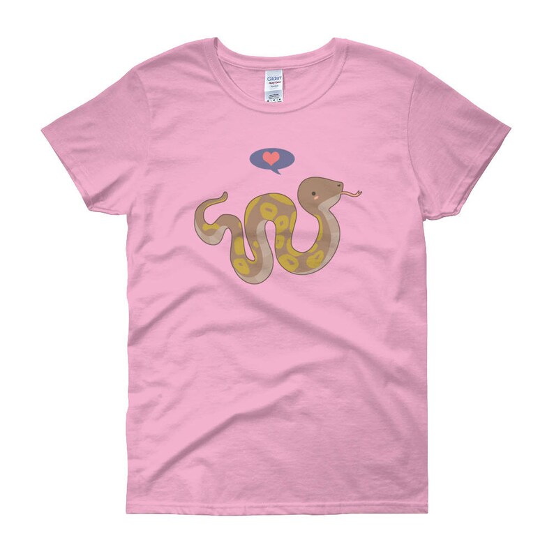 May include: A pink women's t-shirt with a cartoon snake with yellow and brown markings. The snake is holding a heart in its mouth and has a thought bubble above its head.