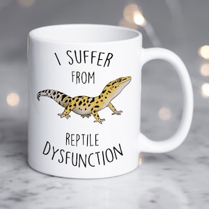 May include: White ceramic mug with a black and yellow gecko illustration and the text "I suffer from reptile dysfunction".