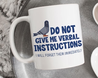 May include: White ceramic mug with a blue and gray cartoon pigeon and the text "Do Not Give Me Verbal Instructions I Will Forget Them Immediately".