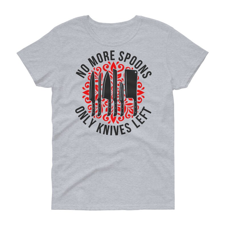 Puede incluir: Camiseta gris con un dise&ntilde;o gr&aacute;fico en negro y rojo. El gr&aacute;fico presenta un c&iacute;rculo con un dise&ntilde;o floral rojo y el texto "No More Spoons Only Knives Left" en negro. Hay seis cuchillos negros dentro del c&iacute;rculo.