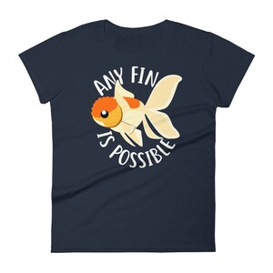 May include: Navy blue women's t-shirt with a white goldfish illustration and the text "Any fin is possible".
