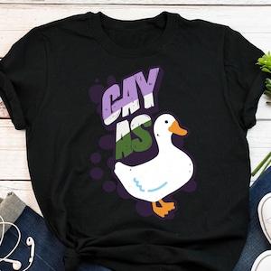 May include: Black t-shirt with a white goose and the text "gay as" in purple, green, and white.