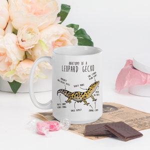 Puede incluir: Taza de cer&aacute;mica blanca con una ilustraci&oacute;n en blanco y negro de un gecko leopardo con etiquetas anat&oacute;micas. El texto en la taza dice "Anatomy of a Leopard Gecko".