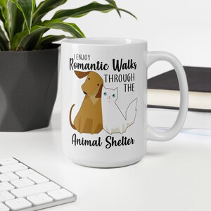 May include: White ceramic coffee mug with a black graphic of a dog and cat with the text "I enjoy romantic walks through the animal shelter".