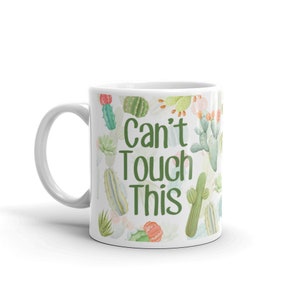 May include: White ceramic mug with a green and white cactus print and the text "Can't Touch This" in green.