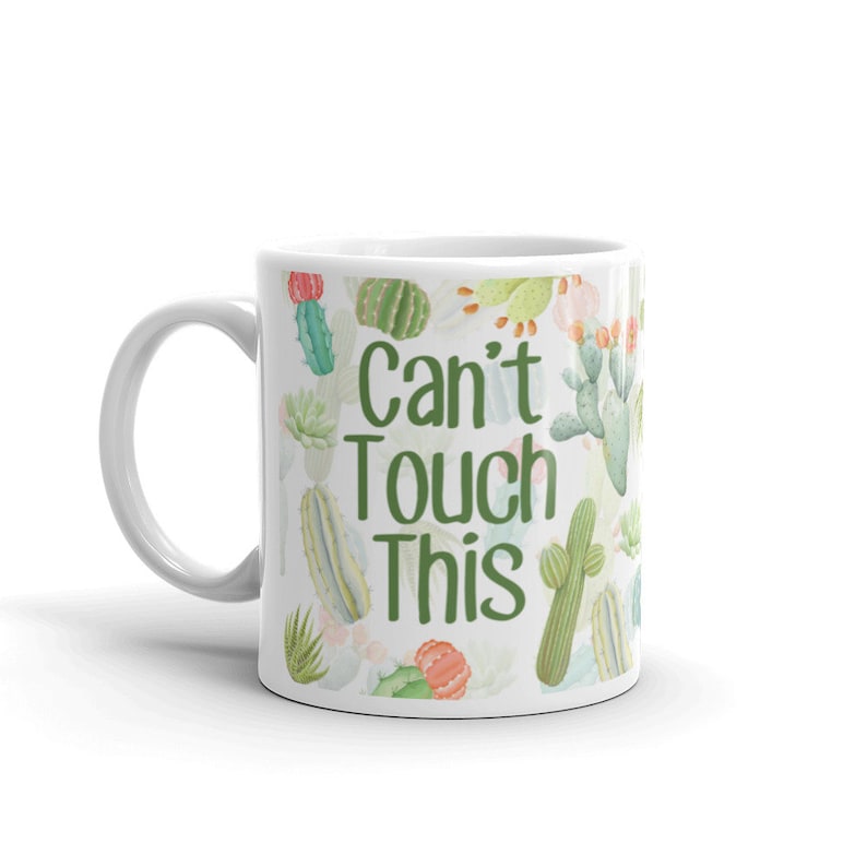 May include: White ceramic mug with a green and white cactus print and the text "Can't Touch This" in green.