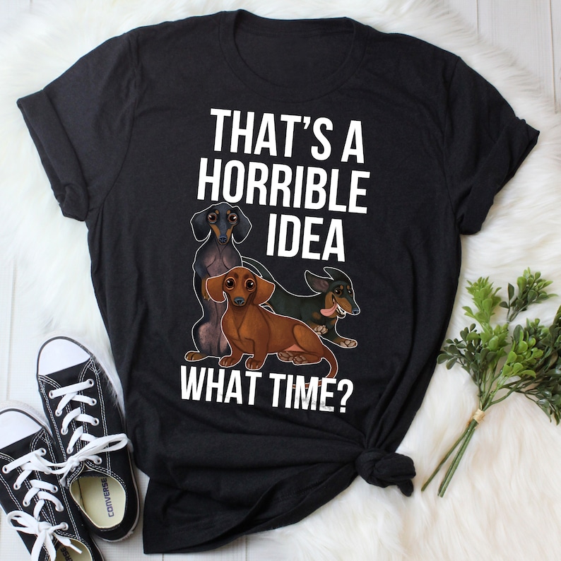 May include: Black t-shirt with a white graphic of three dachshund dogs and the text "That's a horrible idea. What time?"