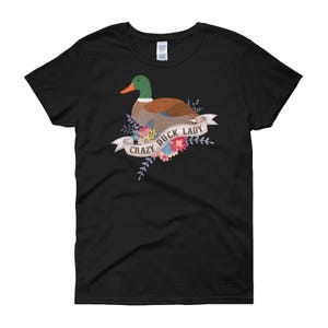 Puede incluir: Camiseta negra con un gr&aacute;fico de un pato verde y marr&oacute;n con flores y el texto "Crazy Duck Lady".