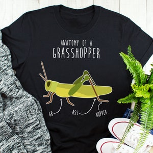 May include: A black t-shirt with a white graphic of a grasshopper and the text "Anatomy of a Grasshopper". The grasshopper is labeled "GR", "ASS", and "HOPPER".