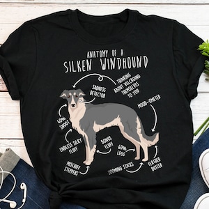 Könnte beinhalten: Ein schwarzes T-Shirt mit einer weißen Grafik eines Silken Windhound Hundes. Die Grafik enthält Text, der die Anatomie des Hundes beschreibt, wie "40% Snoot", "Endless Silky Fluff", "Bonus Fluff", "60% Legs", "Zooming Sticks", "Feather Duster", "Sadness Detector", "Thinking About Velcroing Themselves To You", und "Mood-Ometer".