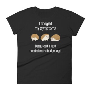 May include: Black women's t-shirt with white text that reads "I Googled my symptoms Turns out I just needed more hedgehogs". Three cartoon hedgehogs are pictured below the text.