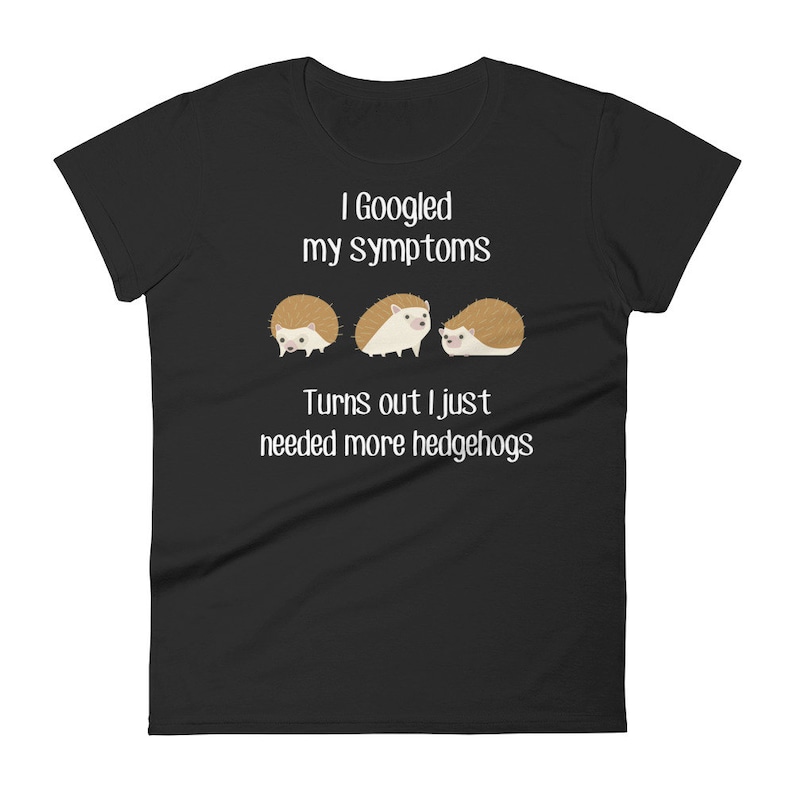 May include: Black women's t-shirt with white text that reads "I Googled my symptoms Turns out I just needed more hedgehogs". Three cartoon hedgehogs are pictured below the text.