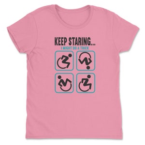 May include: Pink women's t-shirt with the text "KEEP STARING... I MIGHT DO A TRICK" and four black and white icons of a person in a wheelchair performing different actions.