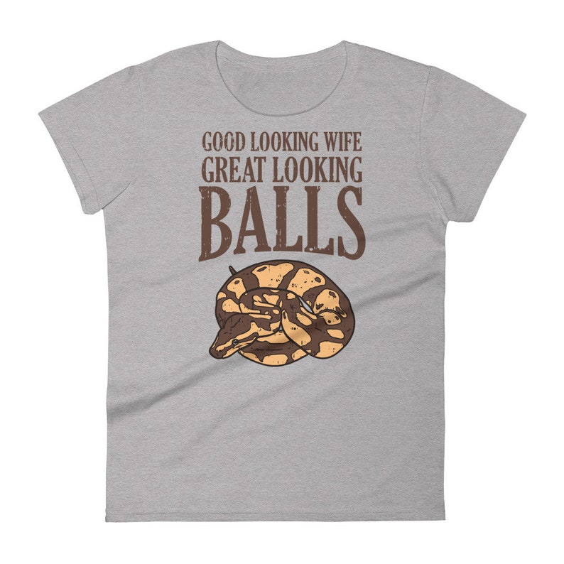 May include: Gray t-shirt with the text "GOOD LOOKING WIFE GREAT LOOKING BALLS" in brown lettering. A brown and yellow snake is curled up below the text.