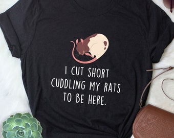 May include: Black t-shirt with a white graphic of a rat sleeping. The text on the shirt reads "I cut short cuddling my rats to be here."