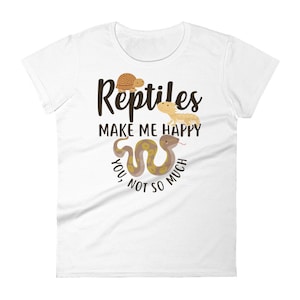 May include: White women's t-shirt with a brown snake, a brown turtle, and a yellow lizard. The text on the shirt reads "Reptiles make me happy, you not so much."