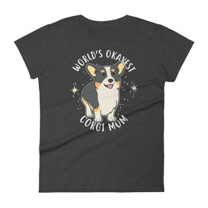 May include: Dark gray t-shirt with a white graphic of a cartoon corgi dog. The text "World's Okayest Corgi Mum" is printed on the shirt.