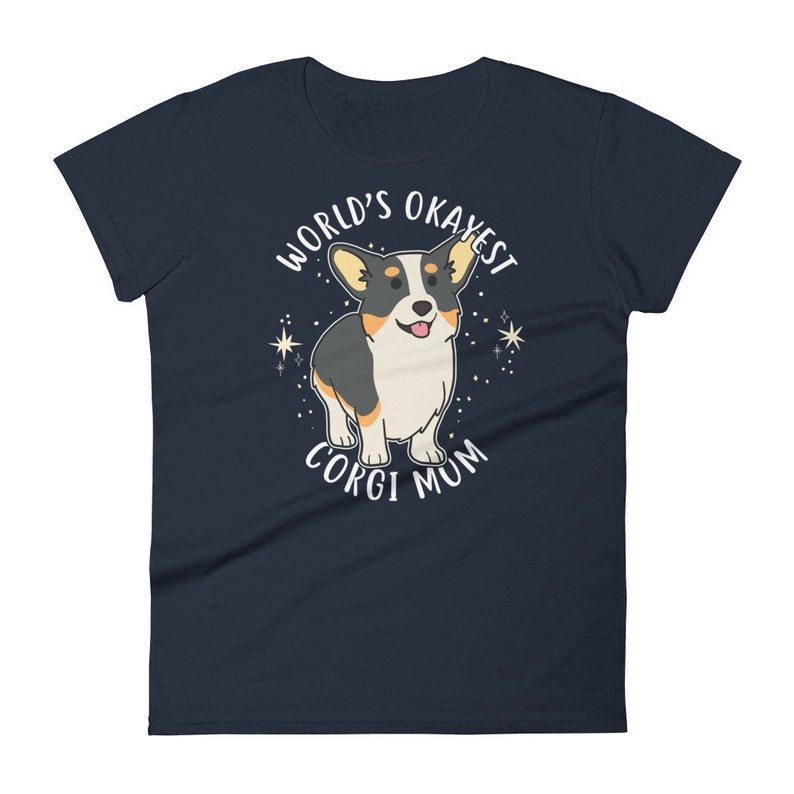 May include: Navy blue women's t-shirt with a white graphic of a corgi dog. The text "World's Okayest Corgi Mum" is printed on the shirt.
