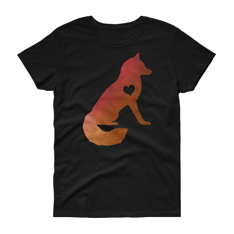 以下が含まれることがあります： 胸にハートを持ったキツネのシルエットが描かれた黒いTシャツ。キツネはオレンジと赤のグラデーションになっている。
