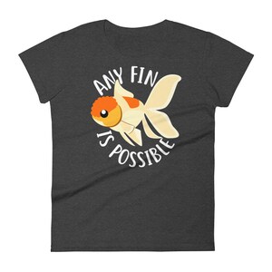May include: A dark heather grey t-shirt with a white graphic of a goldfish and the text "Any Fin Is Possible".