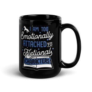 May include: Black coffee mug with a white design that says "I am too emotionally attached to fictional characters". The design also includes a unicorn and an open book.
