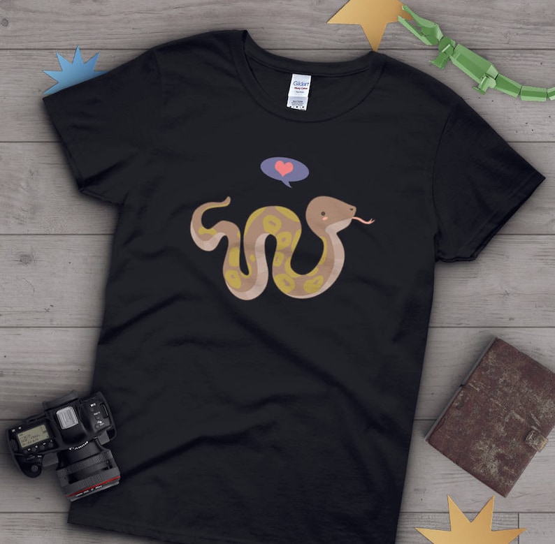 May include: Black t-shirt with a cartoon snake with a heart above its head. The snake is brown and yellow with a light blue thought bubble above its head.