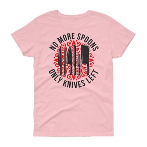 Puede incluir: Camiseta rosa para mujer con un dise&ntilde;o gr&aacute;fico en negro y rojo. El gr&aacute;fico presenta un c&iacute;rculo con el texto "No More Spoons Only Knives Left" y un dise&ntilde;o de cuchillos.