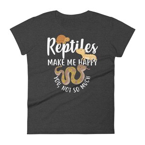 May include: Dark heather grey women's t-shirt with a white graphic that says "Reptiles make me happy, you not so much". The graphic includes a turtle, a bearded dragon, and a snake.