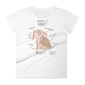 May include: A white t-shirt featuring a cartoon illustration of a rabbit with the text "Anatomy of a Rabbit". The illustration shows different parts of the rabbit labelled with humorous names such as "Vision Beans", "Twitchy Boop Button", and "Chocolate Egg Dispenser".