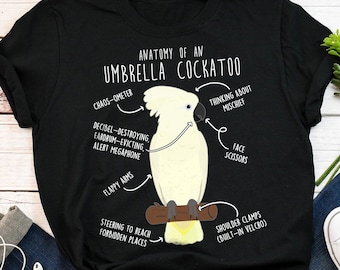 May include: Black t-shirt with a white illustration of a cockatoo with the text "Anatomy of an Umbrella Cockatoo" and a humorous description of the bird's features.