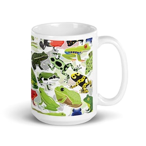 May include: White ceramic mug with a colorful pattern of frogs. The frogs are green, red, yellow, blue, and black. The mug has a white handle.