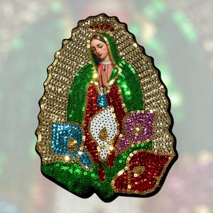May include: A religious icon featuring a depiction of the Virgin Mary, adorned with green, red, and blue sequins. The image is framed by a gold sequined border and includes a detailed illustration of the Virgin Mary.