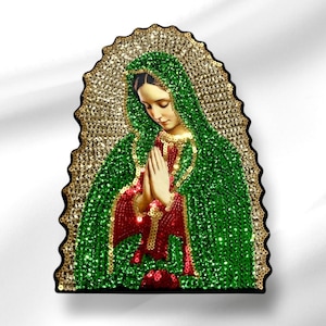 May include: A beaded image of the Virgin Mary, also known as Our Lady of Guadalupe, with a green and gold background. The image is framed in a black frame.
