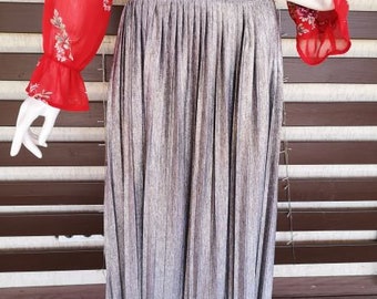 May include: A silver pleated skirt with a subtle shimmer. The skirt is knee-length and has a wide waistband.