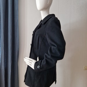 May include: A black wool coat with a double breasted closure and a button on the sleeve.