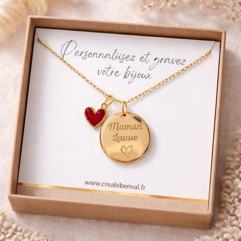 May include: A gold-colored necklace with a pendant that says "Maman Louve" and a small red heart charm. The necklace is displayed in a brown box with the text "Personnalisez et gravez votre bijoux".