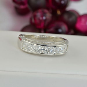 May include: A silver band ring with a row of clear square-shaped stones.