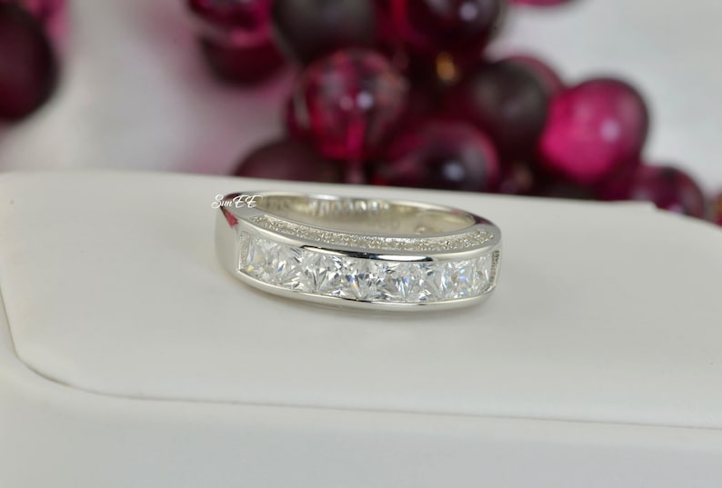 May include: A silver band ring with a row of clear square-shaped stones.