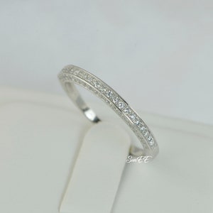 May include: A silver band ring with a row of small clear cubic zirconia stones.