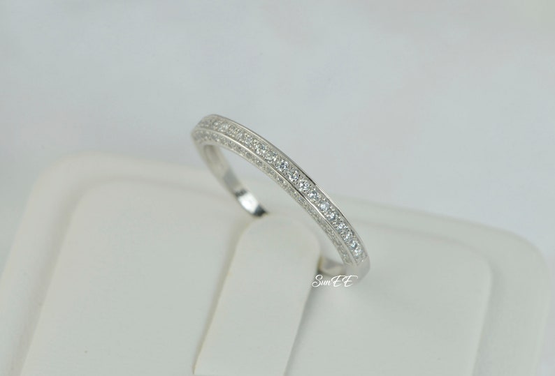 May include: A silver band ring with a row of small clear cubic zirconia stones.