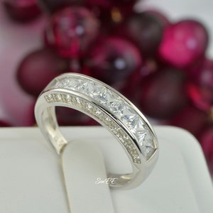 May include: A silver band ring with a row of clear cubic zirconia stones.